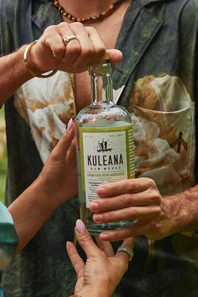 Man and woman holding a bottle of Kula Na`a rum outdoors